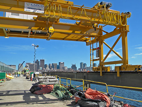 At 105 foot wide, the bridge carries both rail and road connections. For the reconstruction, Capco Crane has built a bespoke 40ft wide double girder gantry crane. This features twin Street 7.5 tonne ZX hoists and a cantilever to accommodate a generator set for power.